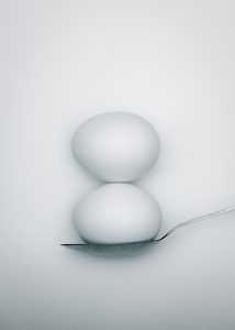 two whole eggs balancing on spoon