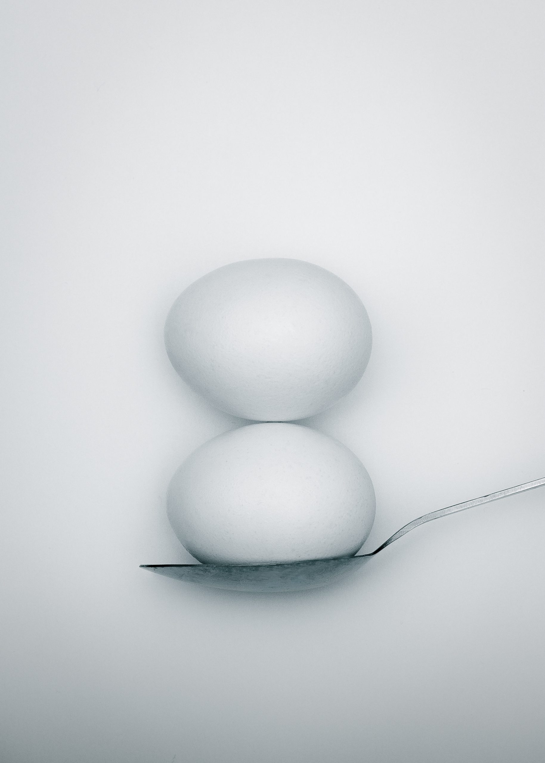 two whole eggs balancing on spoon