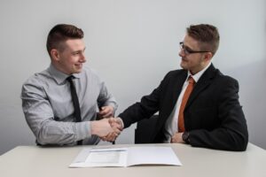 employer and employee shaking hands over employment contract