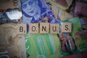 scrabble tiles spelling the word "bonus" laid on top of canadian money