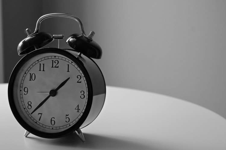 black and white shot of an alarm clock on a table, representing employee rights respecting time away from work