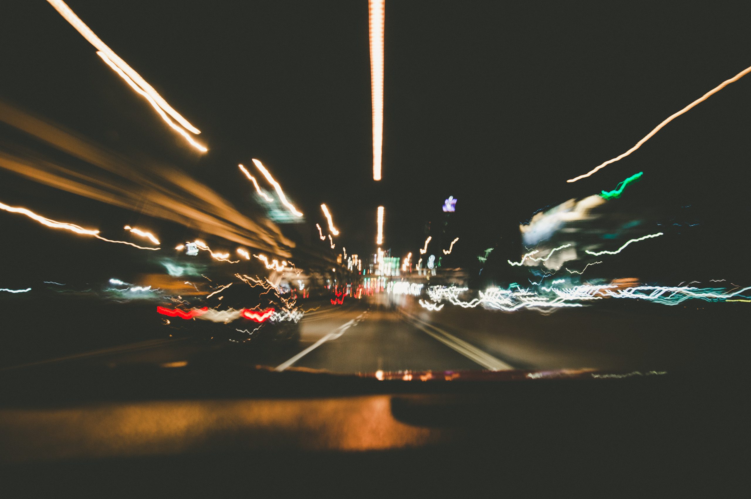 blurred streetlights seen through the windshield of a car in motion