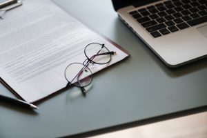 a legal document with a pair of glasses and a laptop on a desk