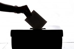A hand placing a vote into a box