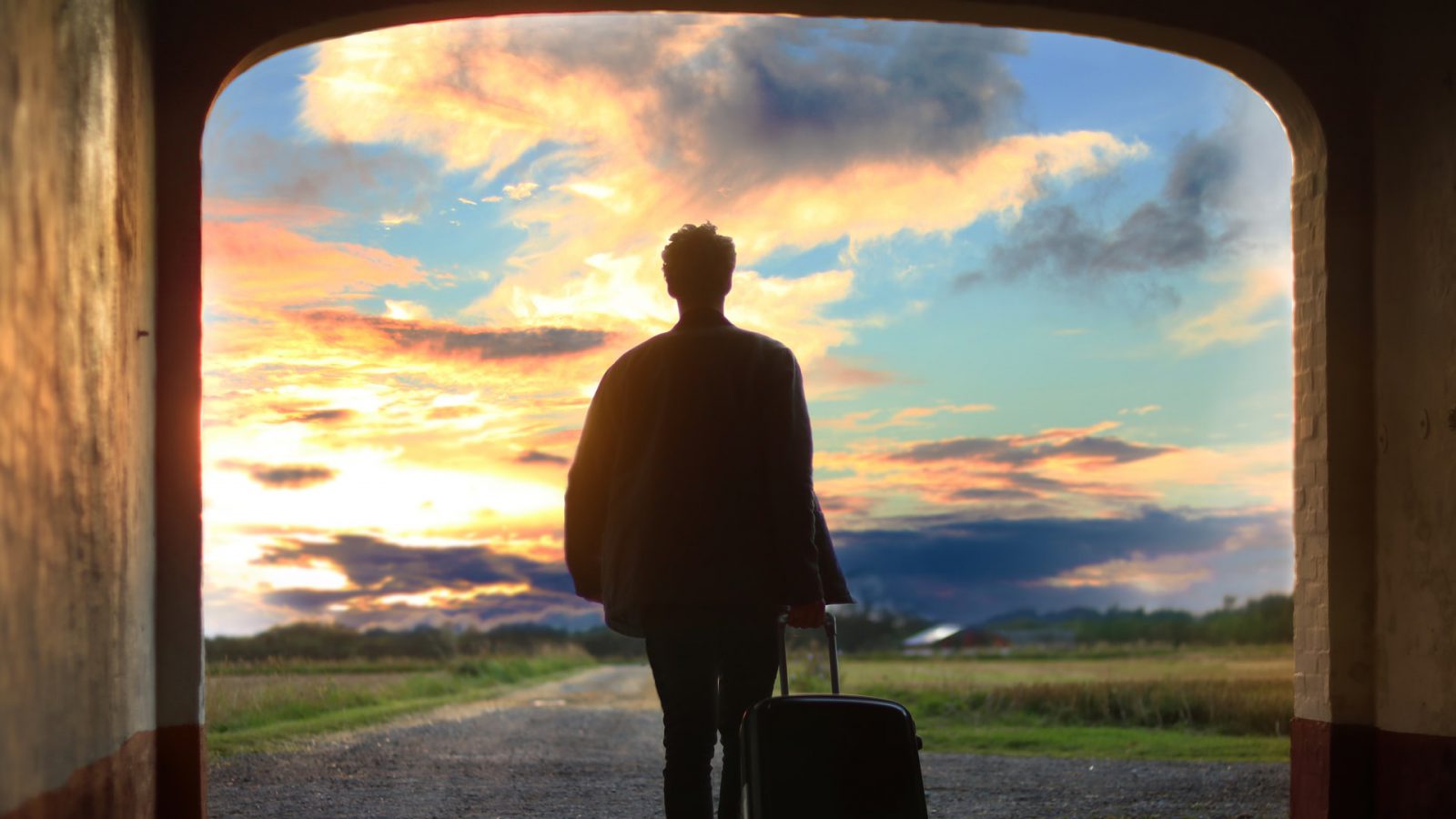 A person walking into a sunset with a suitcase representing leaving a job for another one