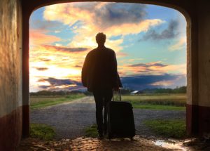 A person walking into a sunset with a suitcase representing leaving a job for another one