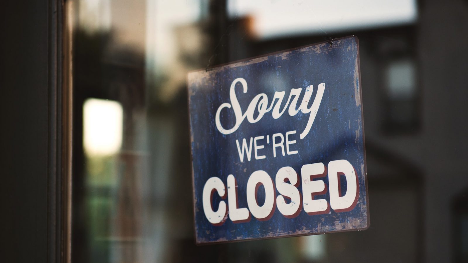 A sign reading "Sorry, We're Closed" in a business window