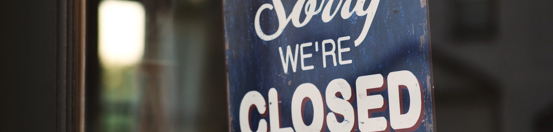 A sign reading "Sorry, We're Closed" in a business window