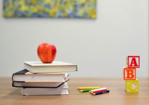 Books, an apple and wooden blocks on a desk representing school closures in Ontario