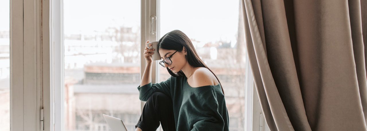 A woman at home on her computer representing someone who has been laid off due to COVID
