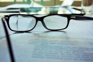 A pair of dark framed glasses atop a stack of printed documents, representing unfair workplace investigations.