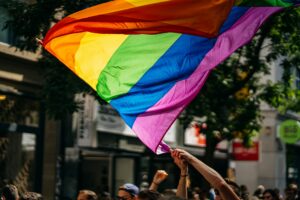 A pride flag is waved over the heads of a crowd on a city street, representing LGBTQ+ employee rights in Ontario.