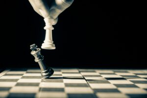 A hand knocks over a black king piece with a white king piece on a chess board, representing wrongful dismissal in Ontario