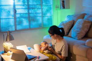 A woman holding a baby in front of her computer while at home, representing employees rights to disconnect in Ontario.