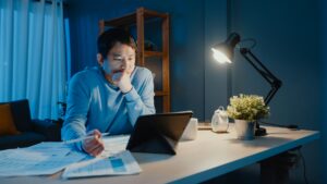 A man working at a desk at night in his home, representing employees right to disconnect in Ontario.
